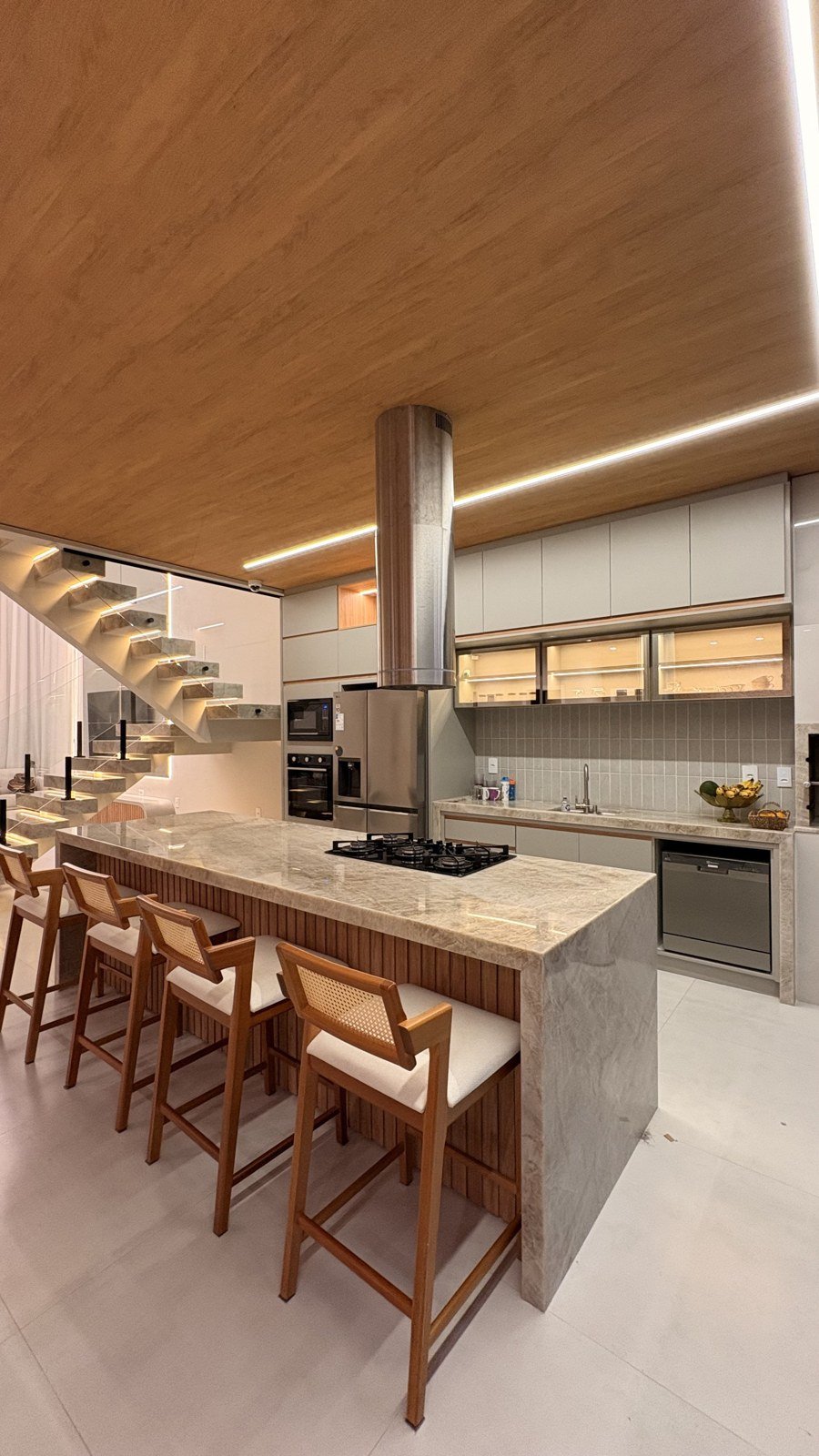 Cozinha planejada com ilha central, coifa e banquetas sob medida